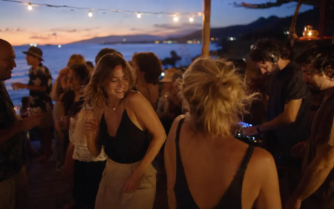 People dancing on a seafront at sunset.
